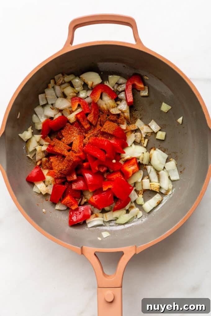 a pink pan with onions, peppers and spices in it