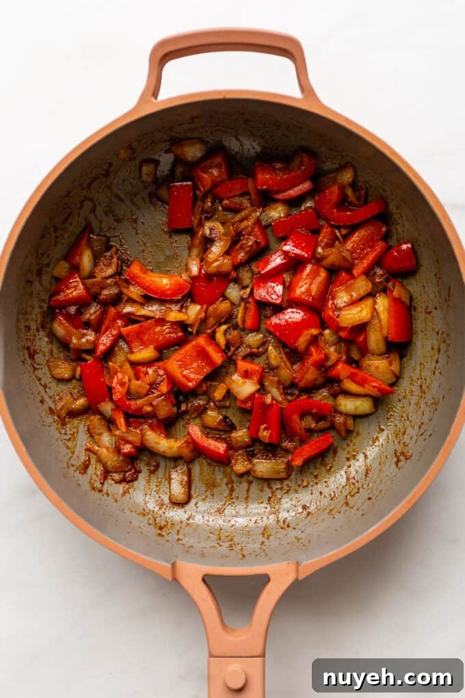 sauteéd onions and red peppers in a pink pan