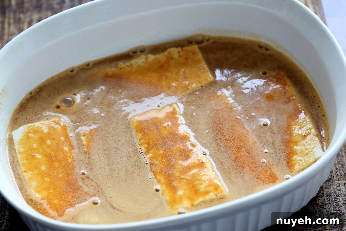Tofu slices in a baking dish with General Tso sauce.