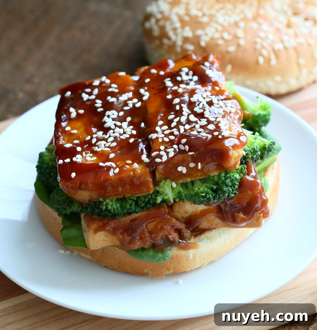 Assembled General Tso's Tofu Sandwich with greens and sesame seeds.