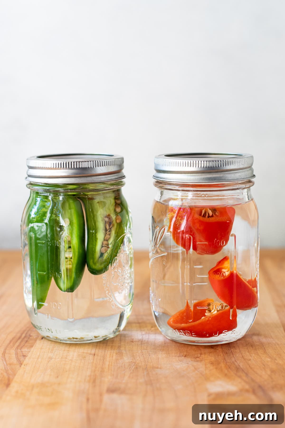 Infusing tequila with Habaneros and Jalapenos in 2 glass mason jars.