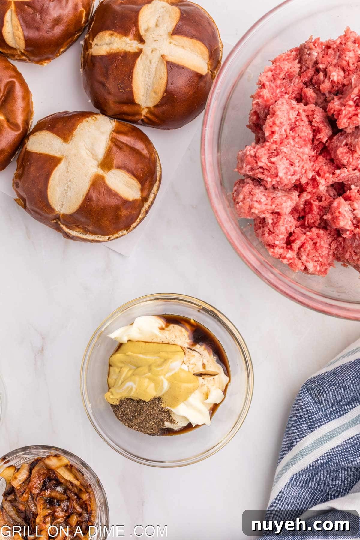Mixing sauce ingredients in a bowl with a bowl of ground beef and pretzel buns on the side