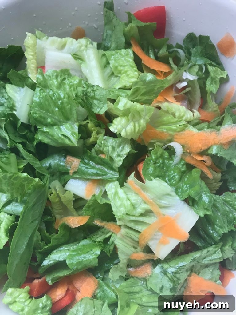 Crisp Green Salad with Creamy Yogurt Dressing 3 a close up of chopped romaine lettuce with shredded carrots and green onions and red peppers