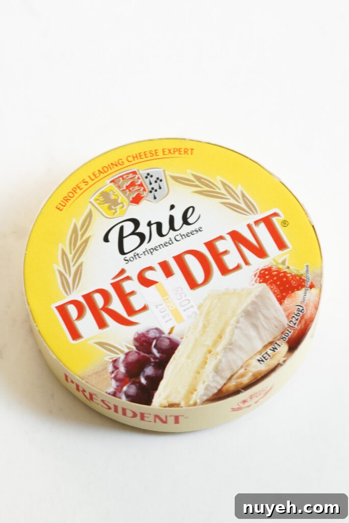 Air Fryer Baked Brie with Honey and Thyme 4 wheel of brie cheese in its yellow packaging on a white table.