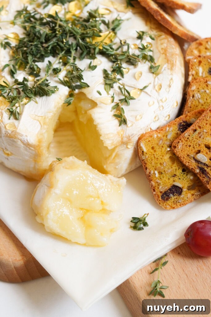 Air Fryer Baked Brie with Honey and Thyme 10 serving platter of air fried brie cheese with honey and herbs served with small dried fruit and nut crisps.