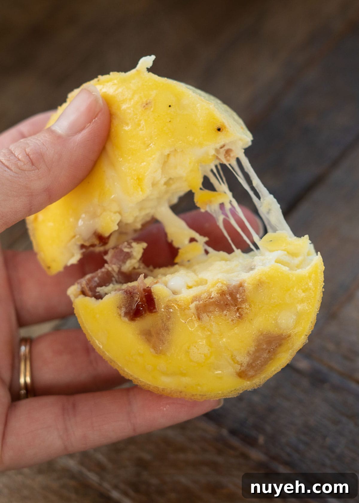 A hand pulling apart a bacon egg bite