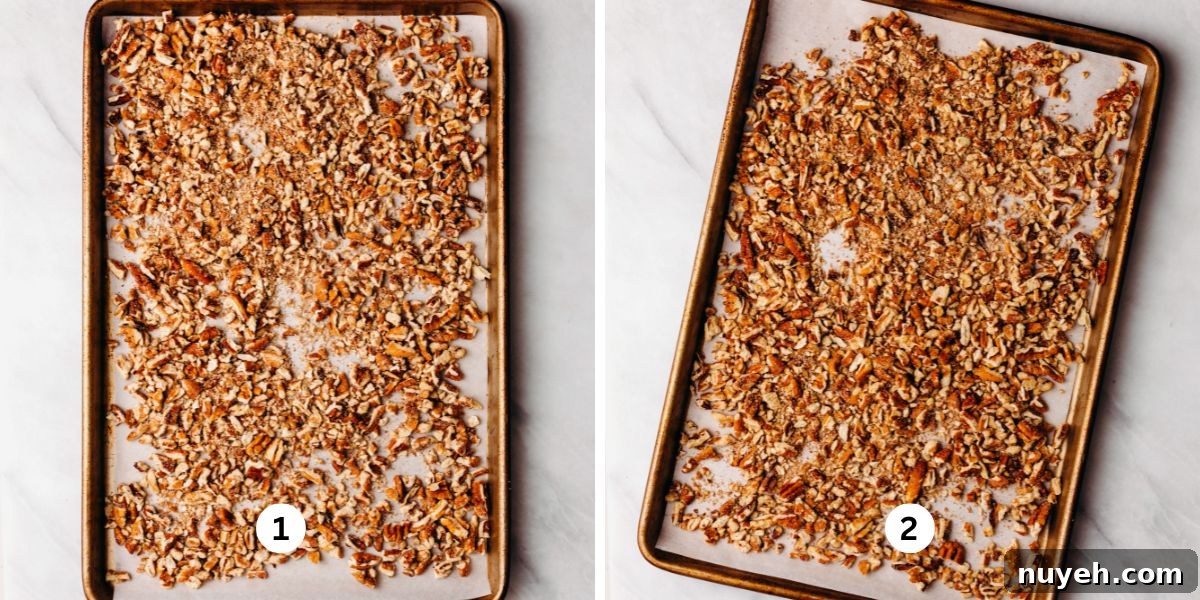 Toasting chopped pecans on a parchment paper lined baking sheet on a white background.