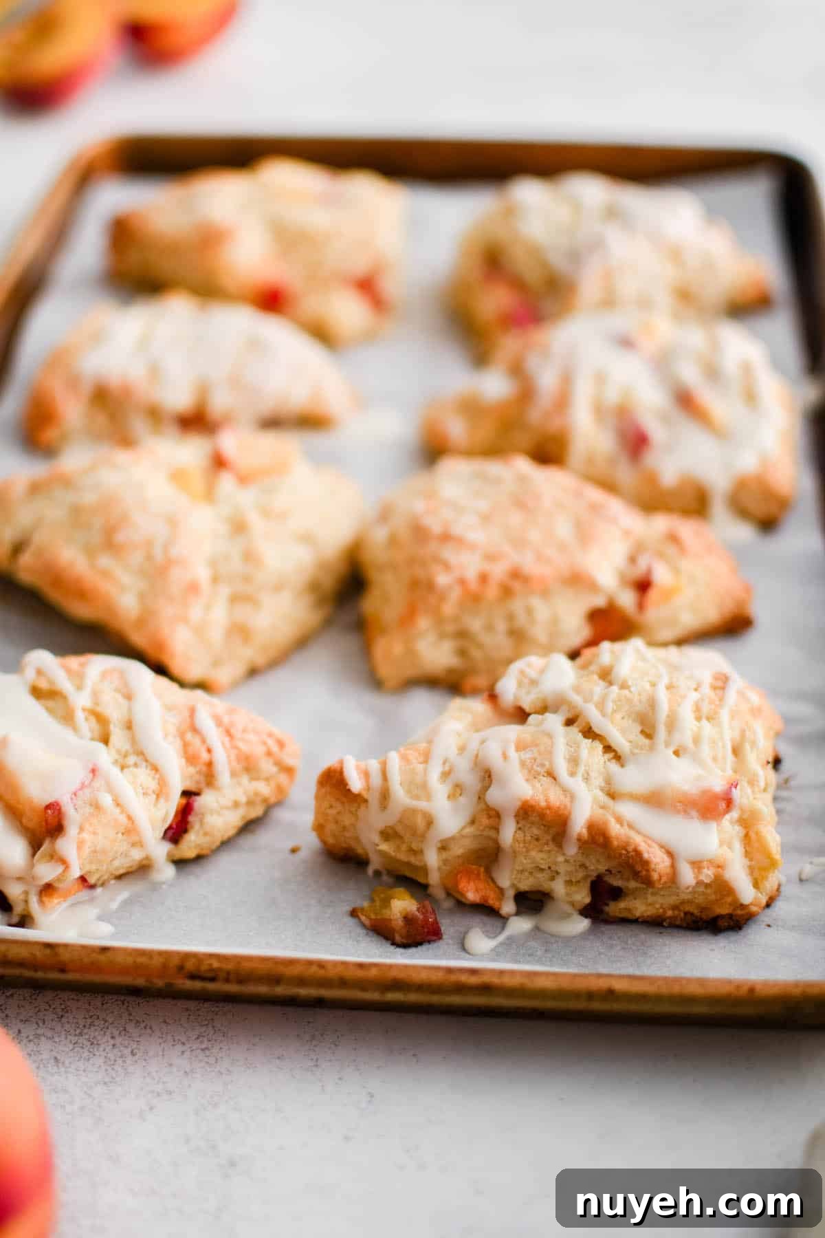 prepared glazed peach scones on a cookie sheet