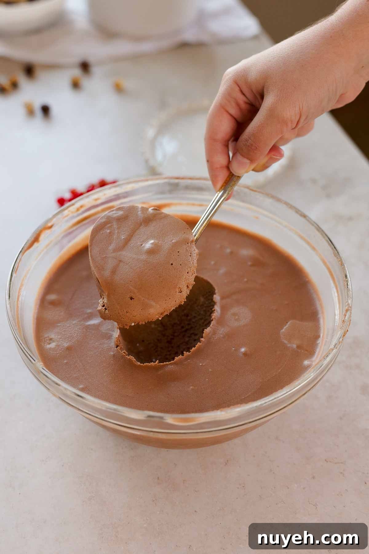 scooping chocolate hazelnut mousse from large glass bowl with a large spoon