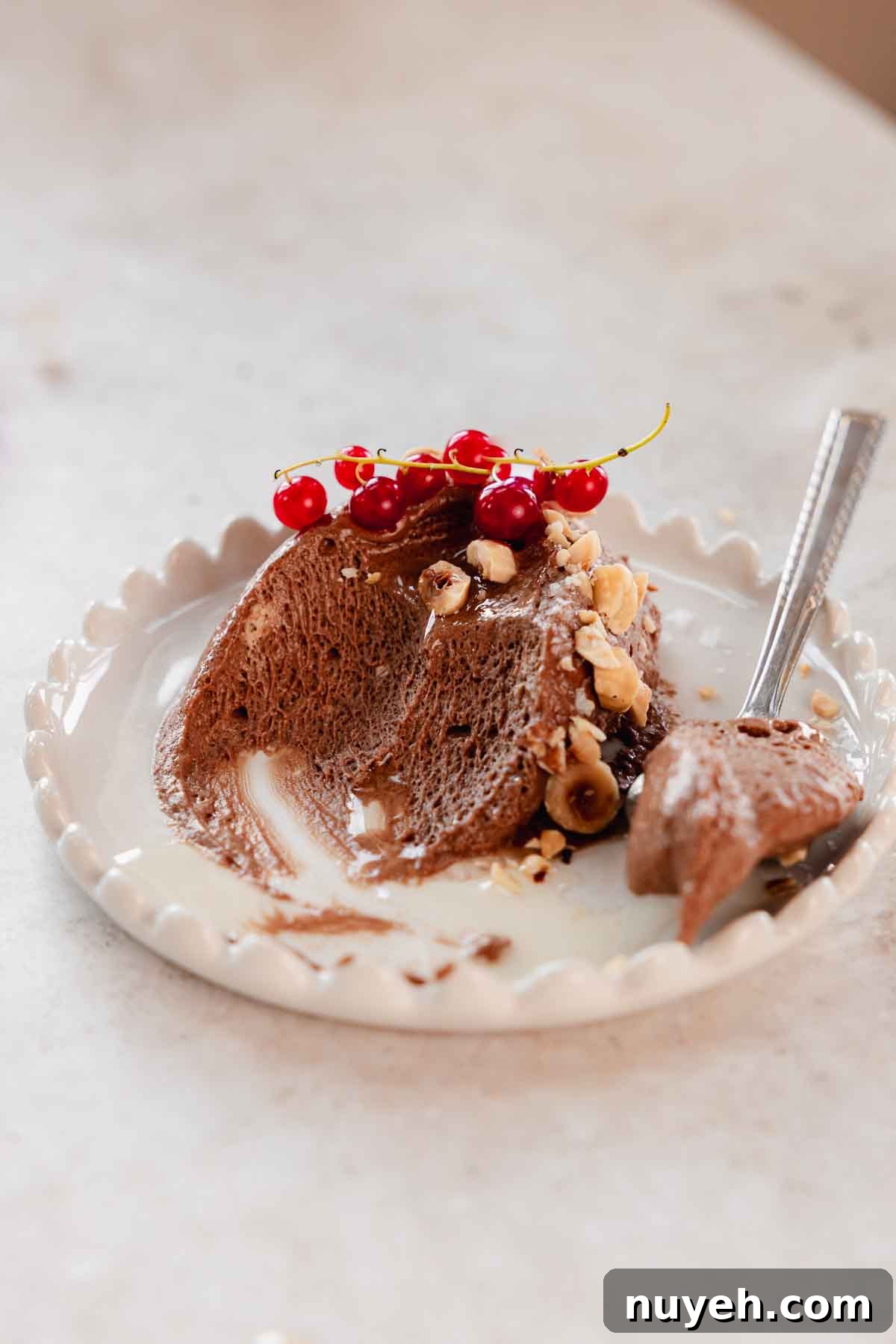 scoop of chocolate mousse with hazelnuts on plate with bites taken from it