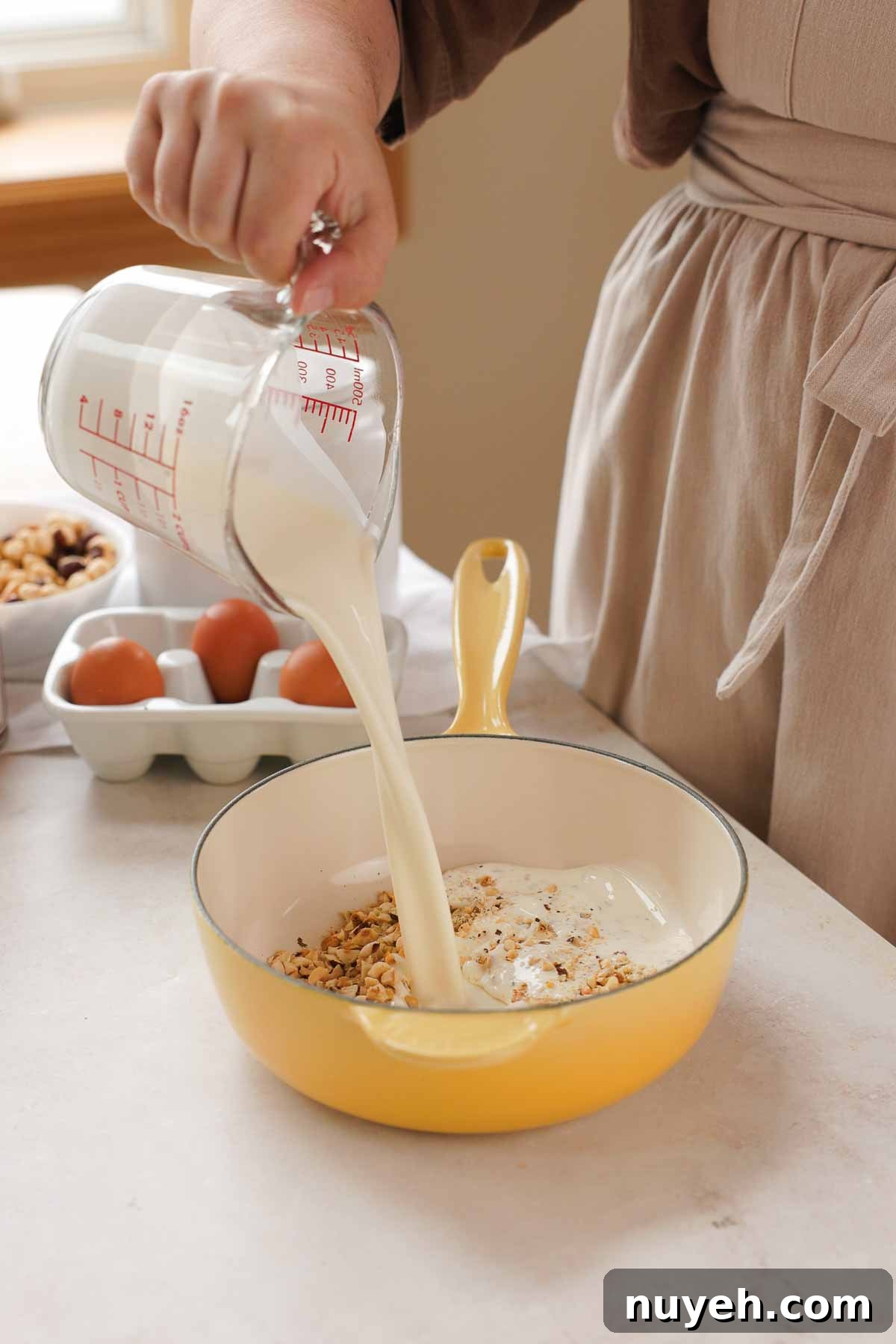 pouring cream from measuring cup into saucepan