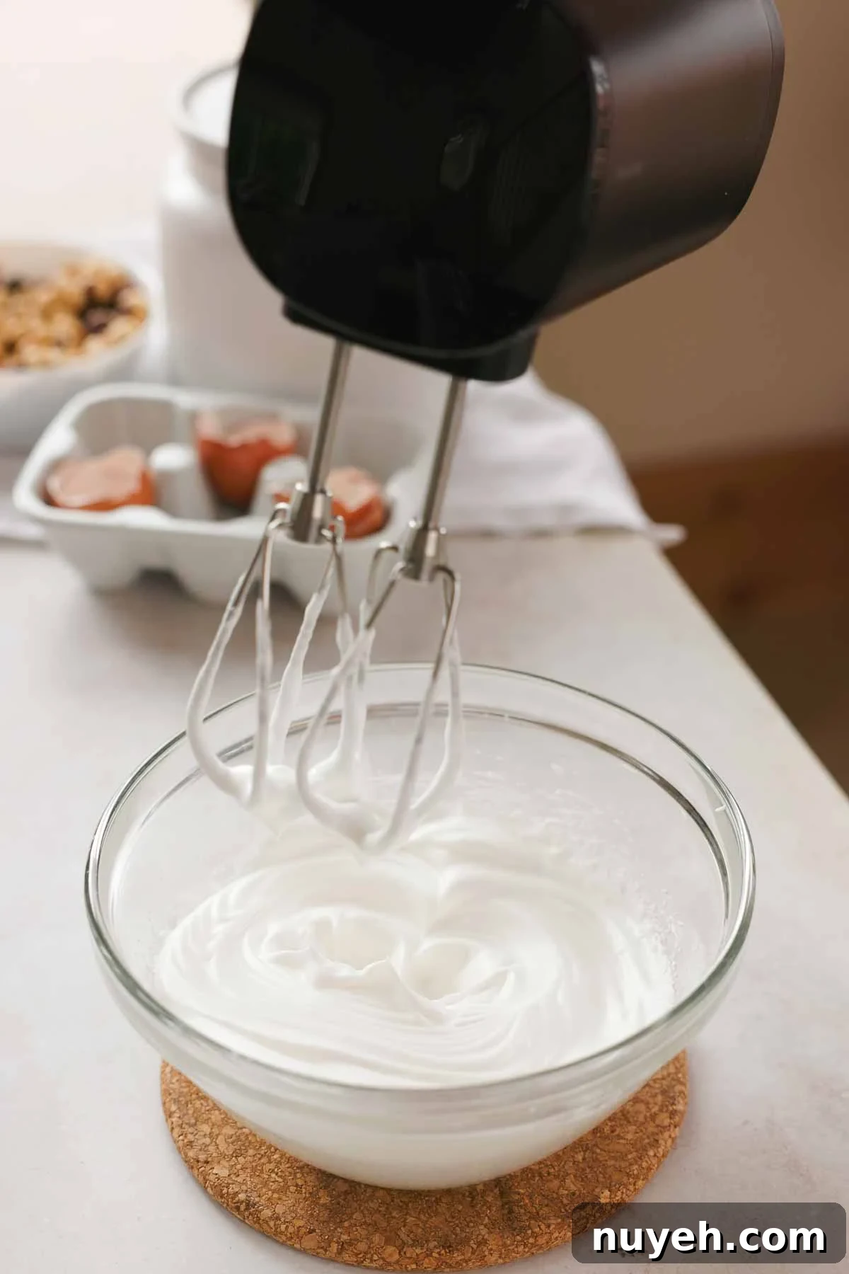 egg whites whipped to medium-stiff peaks in a glass bowl with electric handheld mixer