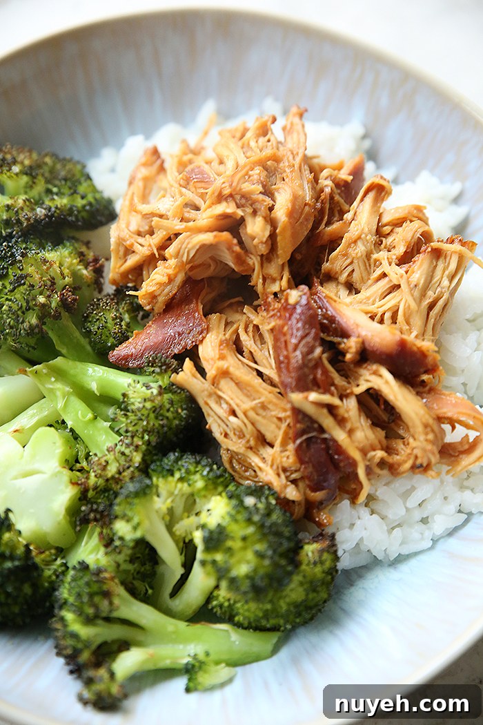 A dinner plate with a serving of honey garlic chicken over white rice along side of a serving of steamed broccoli.