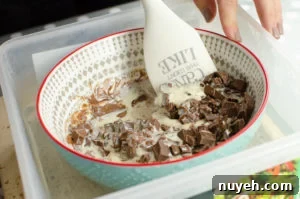 Stirring the hot cream in with the chocolate chunks until its soft and creamy to make the milk chocolate truffles