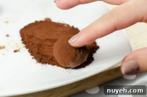 Dusting our milk chocolate truffles with coco powder on a white plate