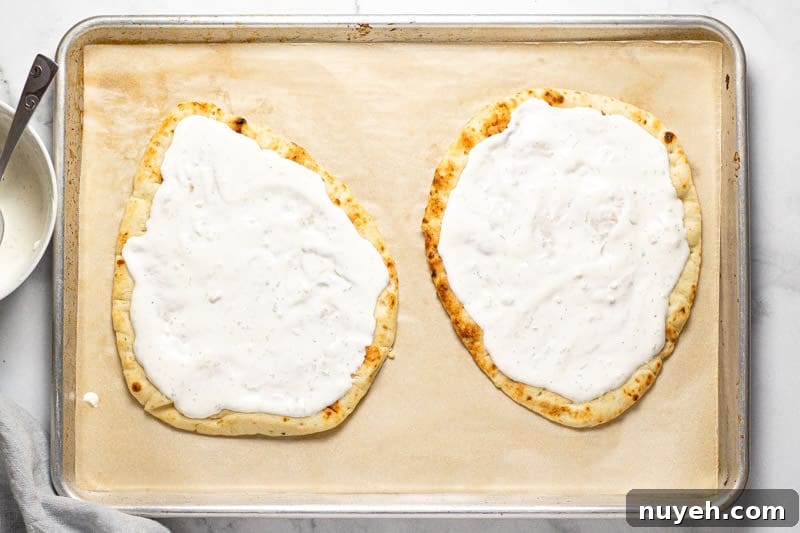 Large baking sheet with two Mexican street corn flatbreads with creamy sauce on them