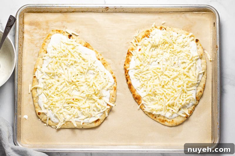 Large baking sheet with two Mexican street corn flatbreads with creamy sauce and cheese on them