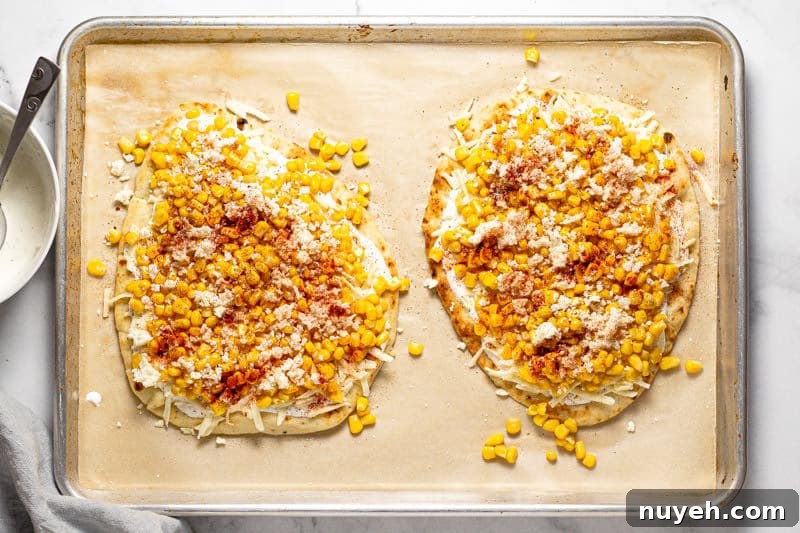 Large baking sheet with two Mexican street corn flatbreads ready to be baked in the oven 