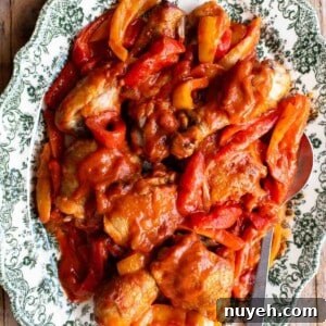 A close up of chicken and peppers on a green and white servings plate.