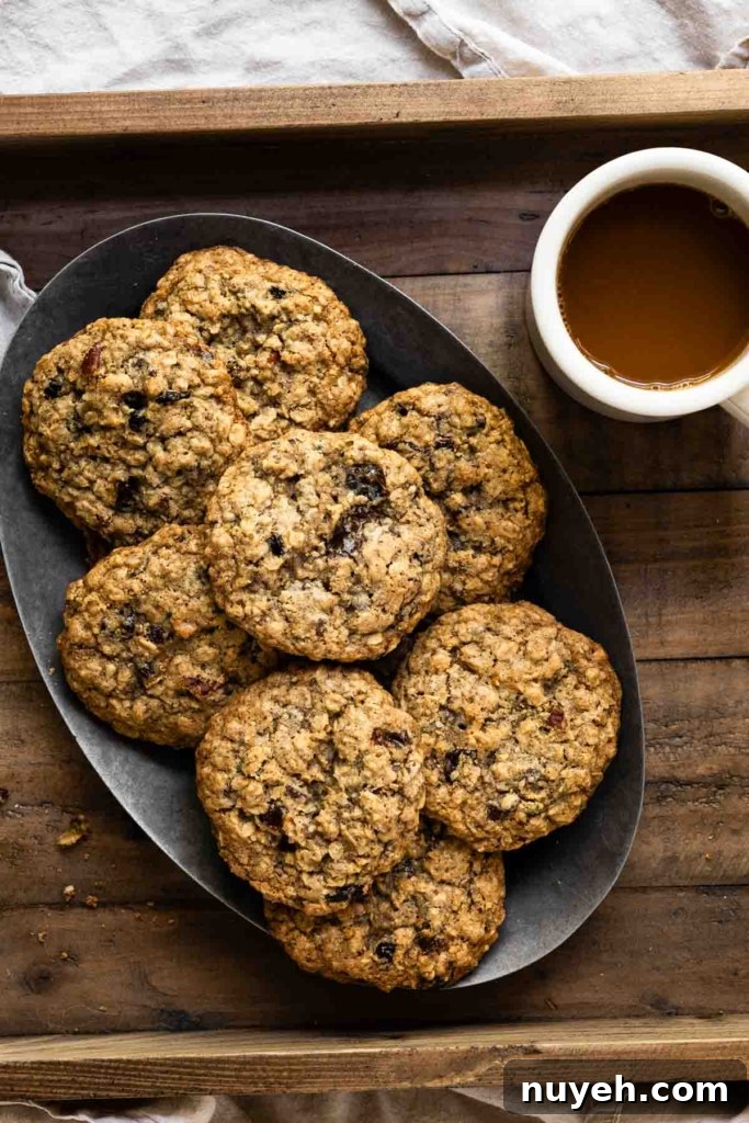 Oval plate filled with a stack of oatmeal cookies next to a cup of coffee.