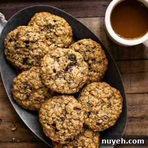 Oval plate filled with a stack of oatmeal cookies next to a cup of coffee.