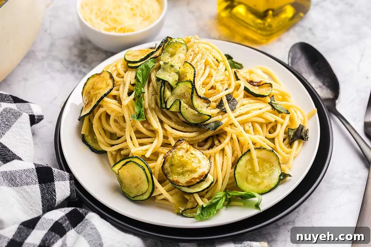 A plate of pasta alla Nerano featuring spaghetti with sautéed zucchini and fresh basil, served with a fork on the side.