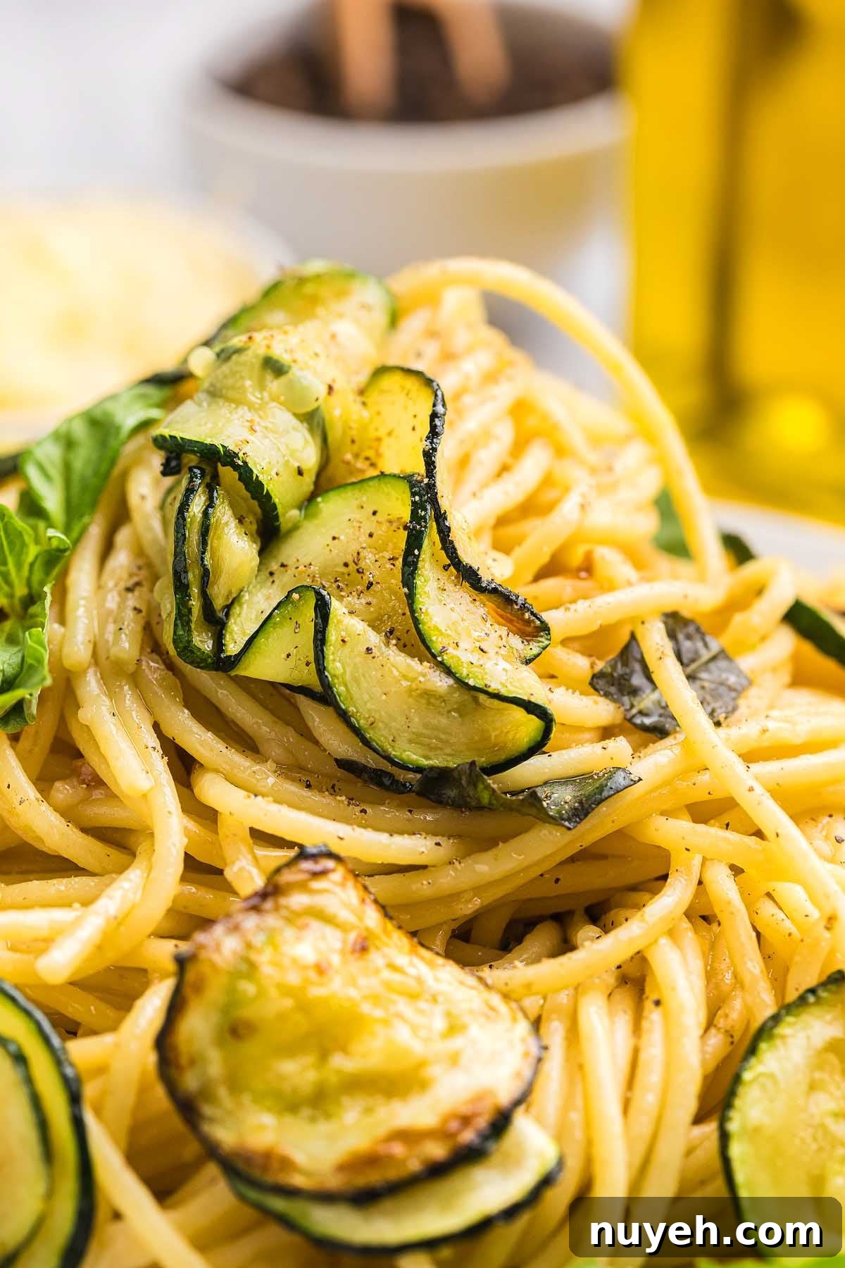 Spaghetti pasta alla Nerano topped with sautéed zucchini slices, garnished with black pepper and fresh basil.