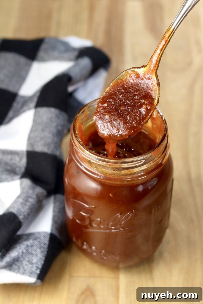 Thick BBQ Sauce on a spoon from a mason jar, black and white check napkin to the side