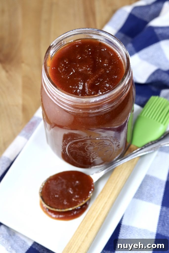 Homemade bbq sauce in a mason jar, spoonful to the side on a white plate