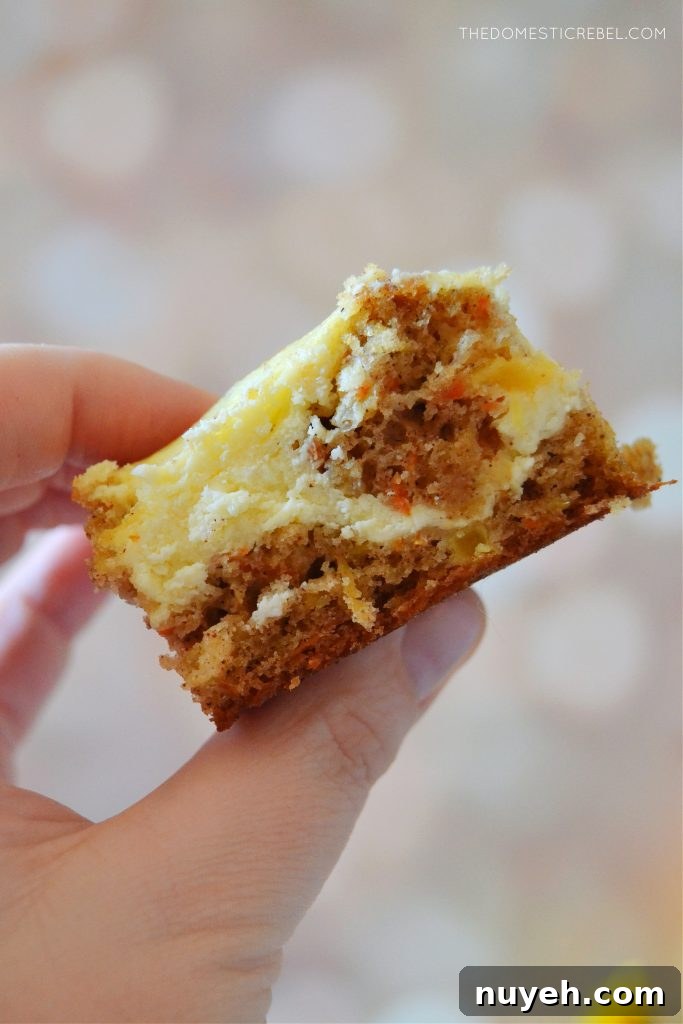 Carrot Cake Cheesecake Bars with Cream Cheese Frosting Recipe 4 author holding a slice of carrot cake cheesecake bars against a light spotted background