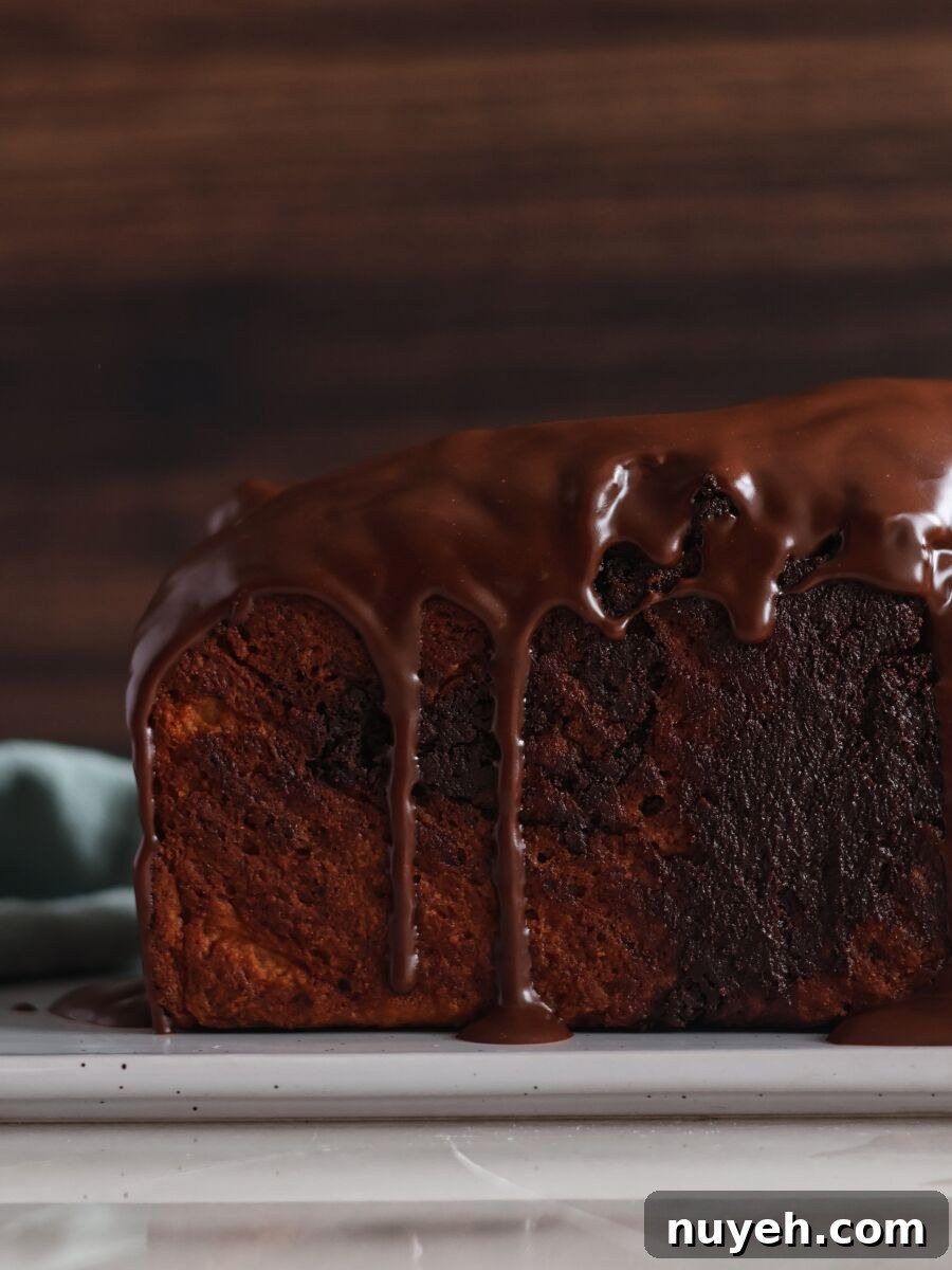 side view of whole chocolate babka with glaze dripping down it.