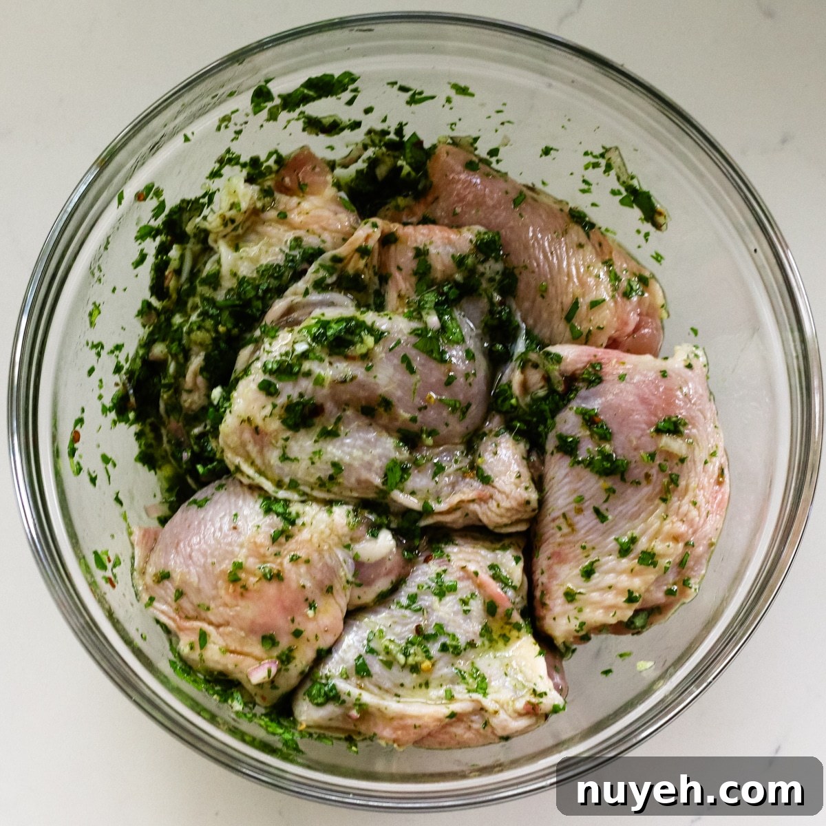 Grilled Chimichurri Chicken Thighs Recipe 7 seasoned chimichurri chicken thighs in glass bowl.