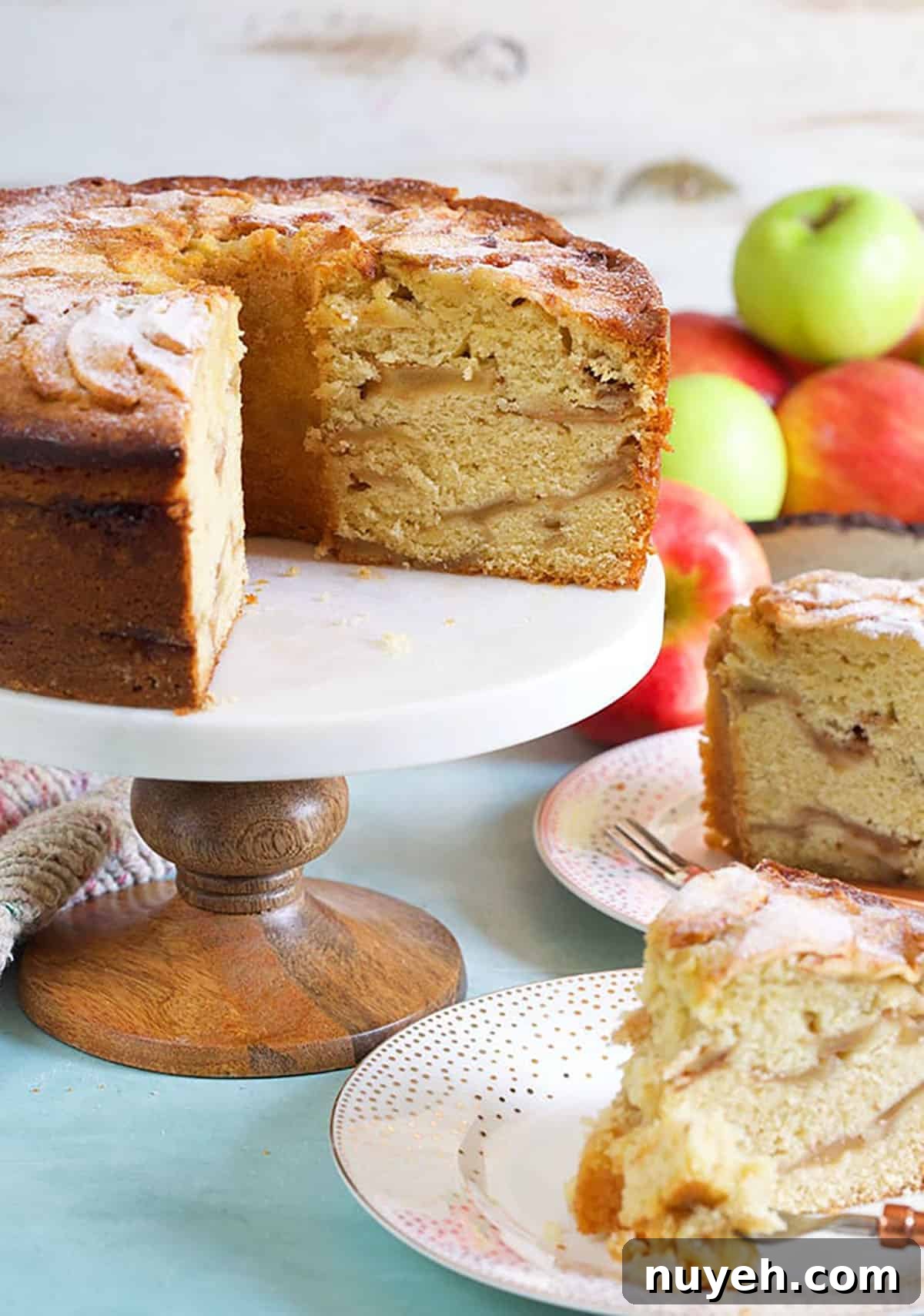 Traditional Jewish Apple Cake Recipe 4 Jewish apple cake with two slices cut out and apples in the background.