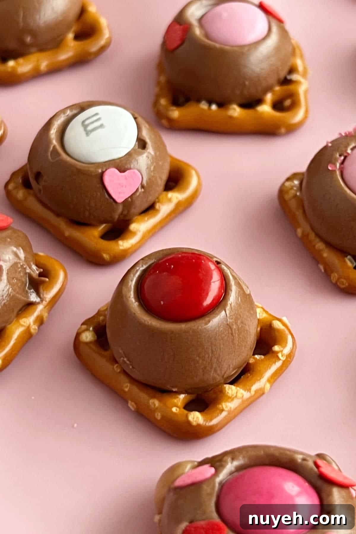 Rolo pretzel bites with M&M's on pink plate.