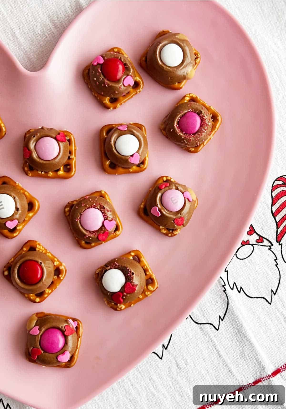 Rolos pretzel treats with Valentine's day candies on pink plate.