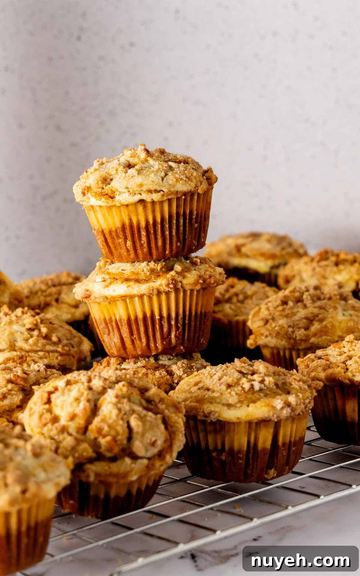 Pumpkin cheesecake muffins stacked on cooling rack.