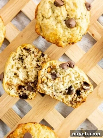 Chocolate Chip Banana Muffins scattered on a serving tray with one cut in half.