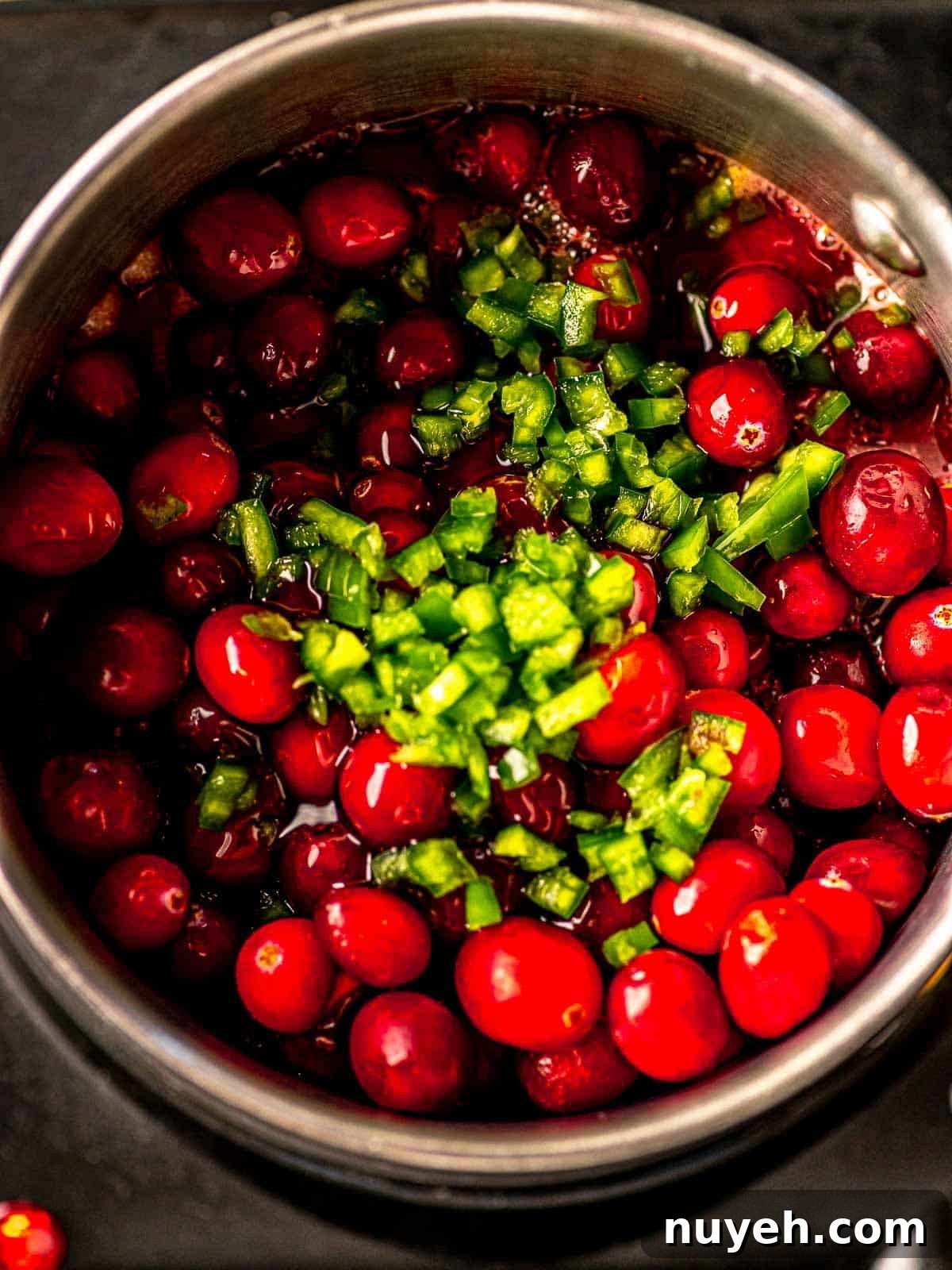 Cranberries and diced jalapeños in a saucepan.