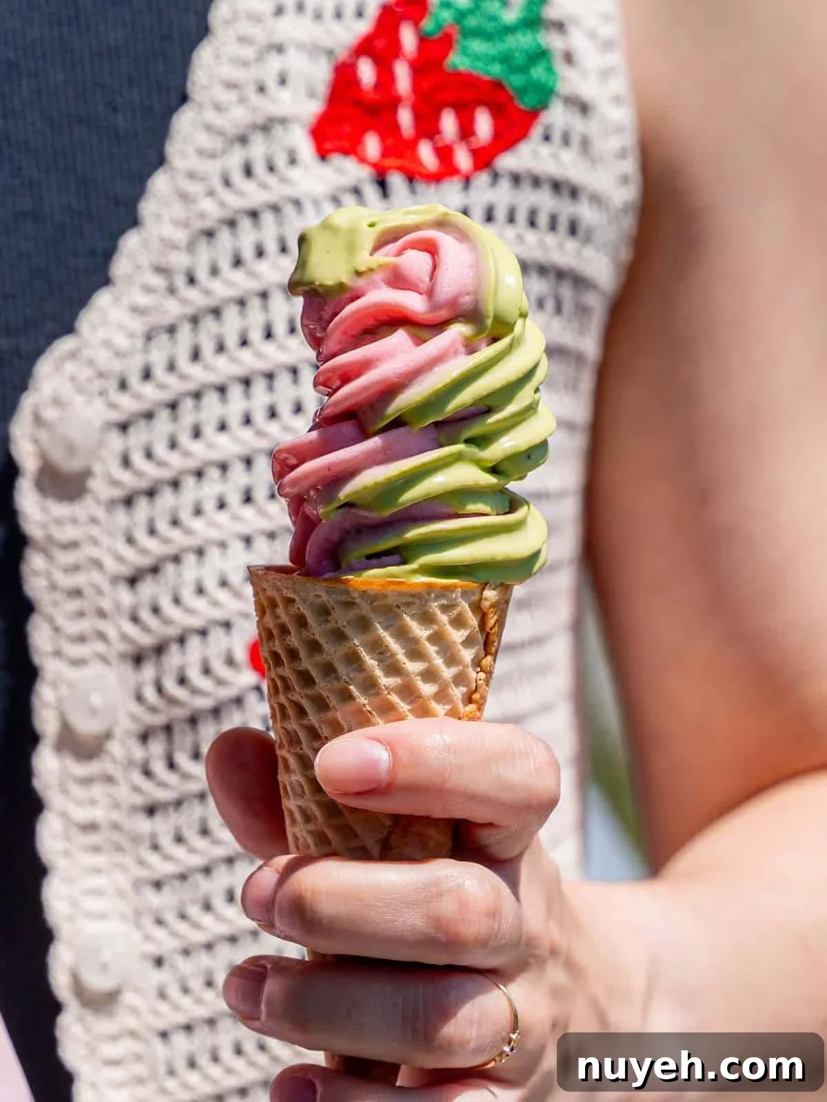 Strawberry matcha ice cream swirled in a sugar cone.