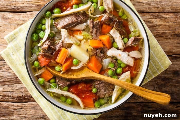 A bowl of green bay booyah on a green striped napkin on a wooden table with a wood spoon