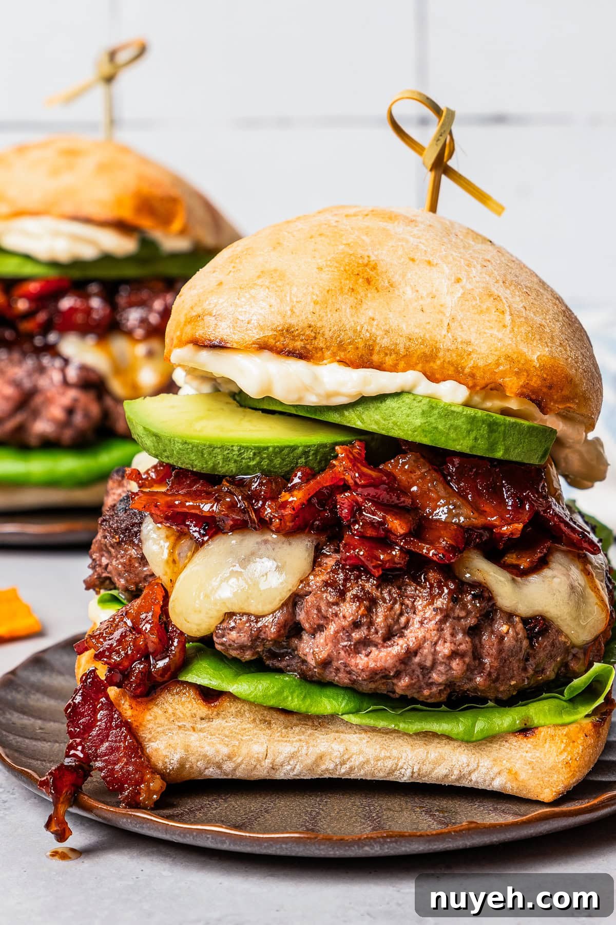Close up of an assembled California burger on a brown stoneware plate.