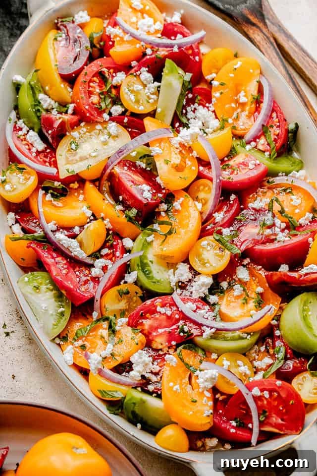 wedges of colored tomatoes topped with slices of red onions and crumbled feta cheese