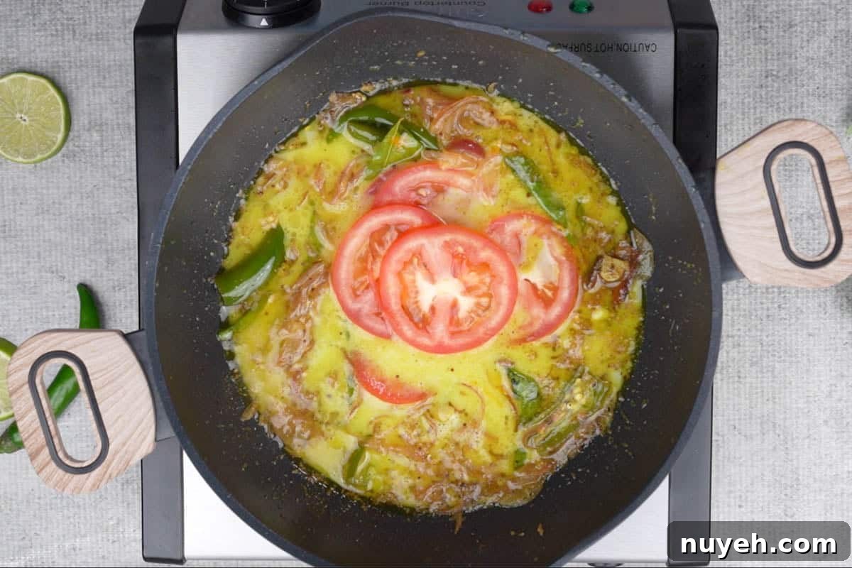 Thin coconut milk and tomato added to the pan.