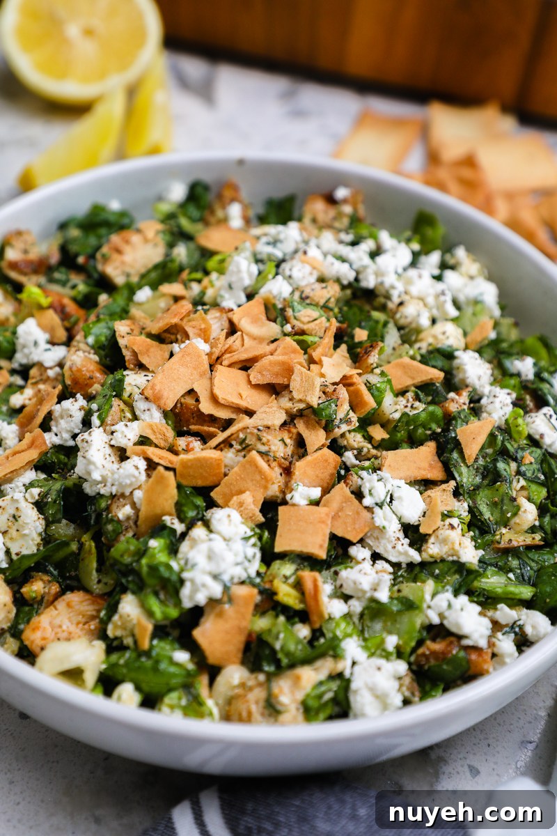 Crisp Chopped Chicken Salad with Feta and Lemon Vinaigrette 7 A side view of a white serving bowl filled with chopped chicken feta salad served with pita chips on the side
