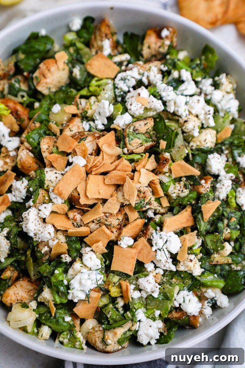 Crisp Chopped Chicken Salad with Feta and Lemon Vinaigrette 8 An overhead view of a white bowl filled with chopped chicken feta salad garnished with crushed pita chips
