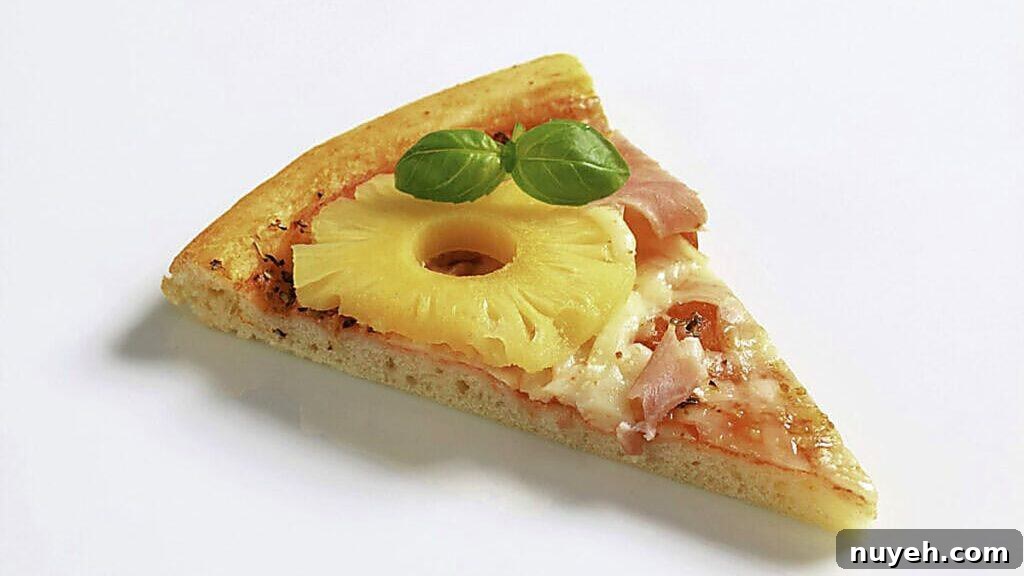 A slice of pizza topped with ham, pineapple, melted cheese, and two fresh basil leaves on a plain white background.