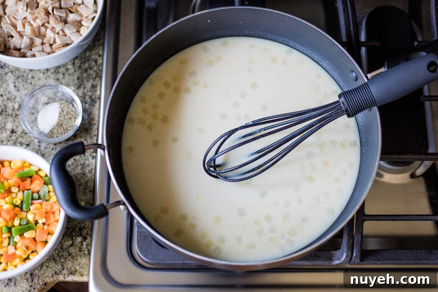 skillet on stove with milk and broth whisked into cooked onions