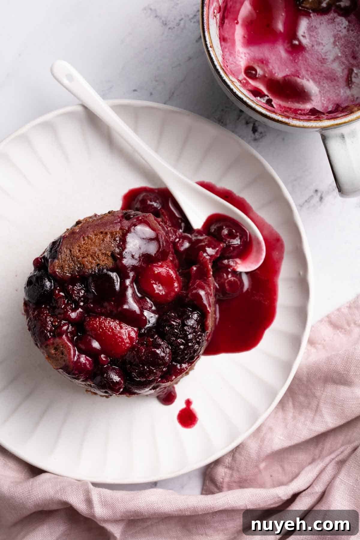 chocolate berry mug cake turned out on plate with mug on the side