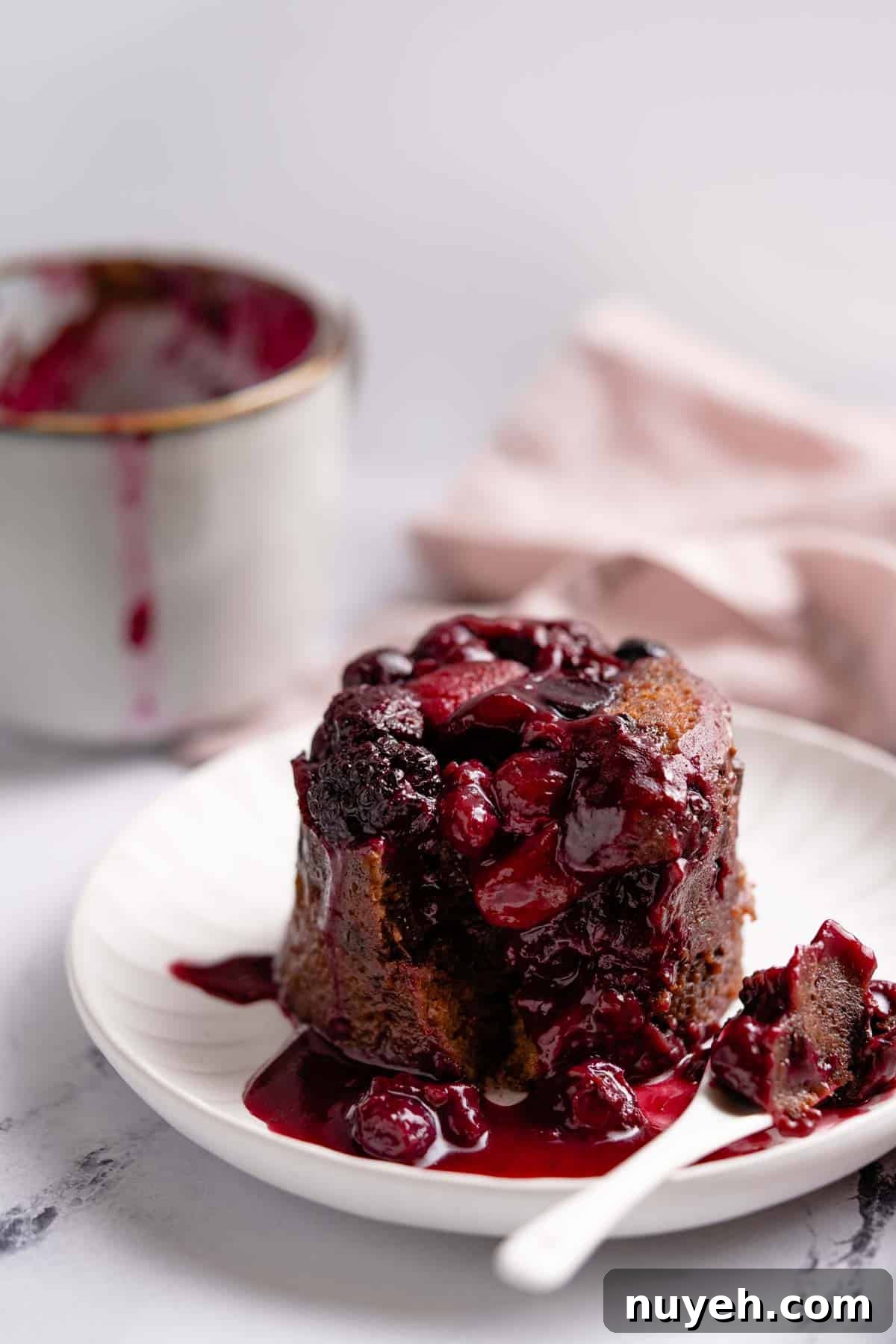 chocolate berry mug cake on plate with mug and napkin in background