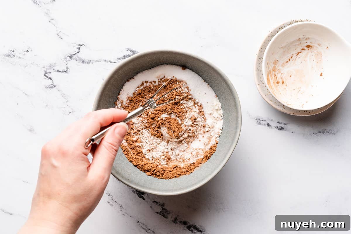 dry ingredients being mixed in small bowl with small empty bowls on the side